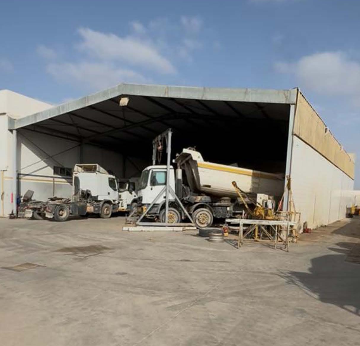 Hangar ouvert à charpente métallique abritant des camions